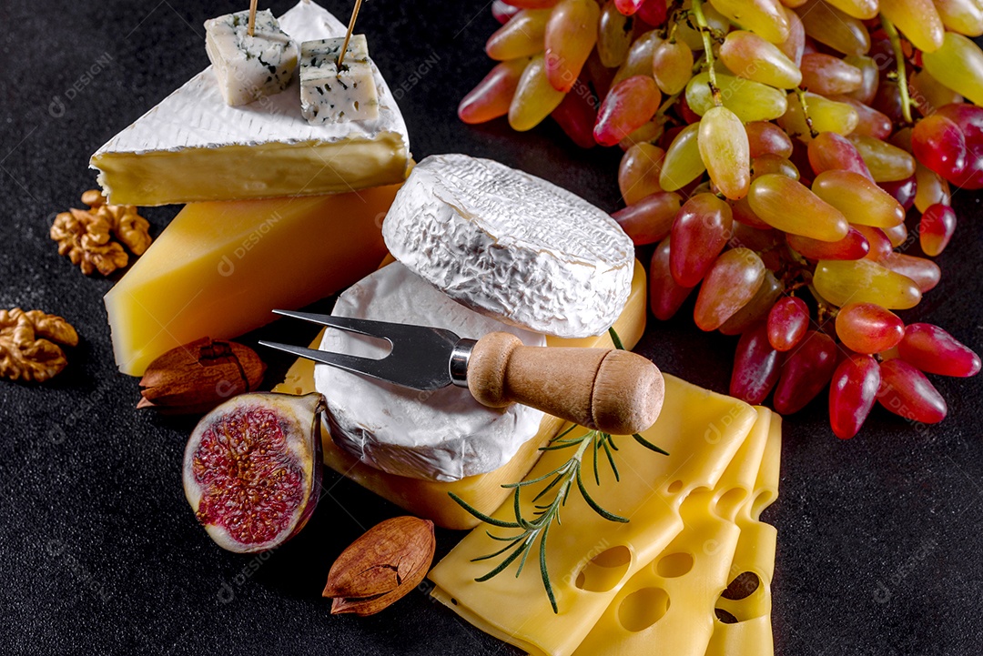 Lindo delicioso queijo camembert, parmesão, brie com uvas e figos em uma tábua de madeira.