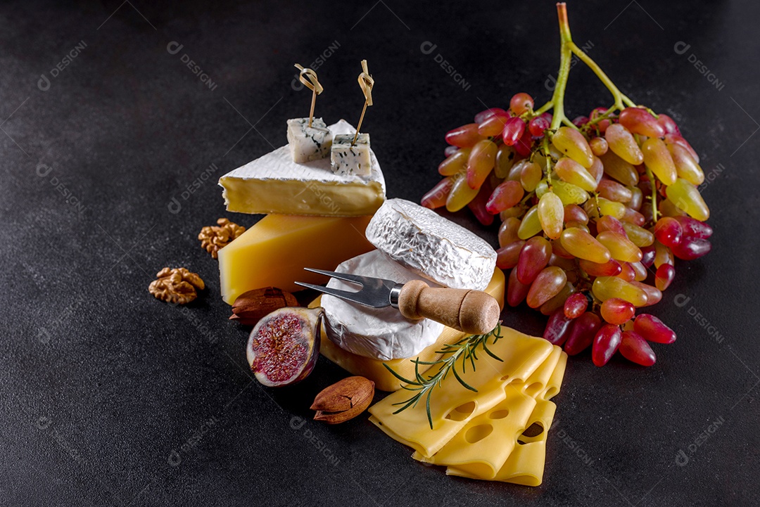 Lindo delicioso queijo camembert, parmesão, brie com uvas e figos em uma tábua de madeira.