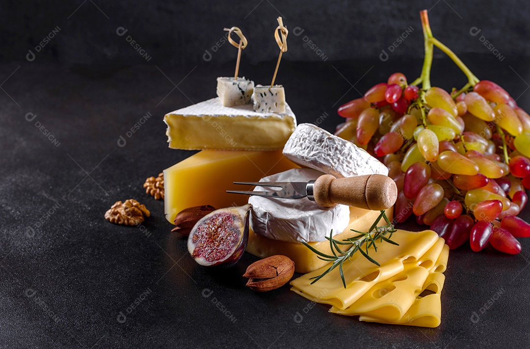 Lindo delicioso queijo camembert, parmesão, brie com uvas e figos em uma tábua de madeira.