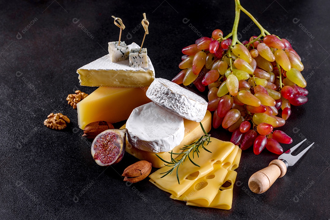 Lindo delicioso queijo camembert, parmesão, brie com uvas e figos em uma tábua de madeira.