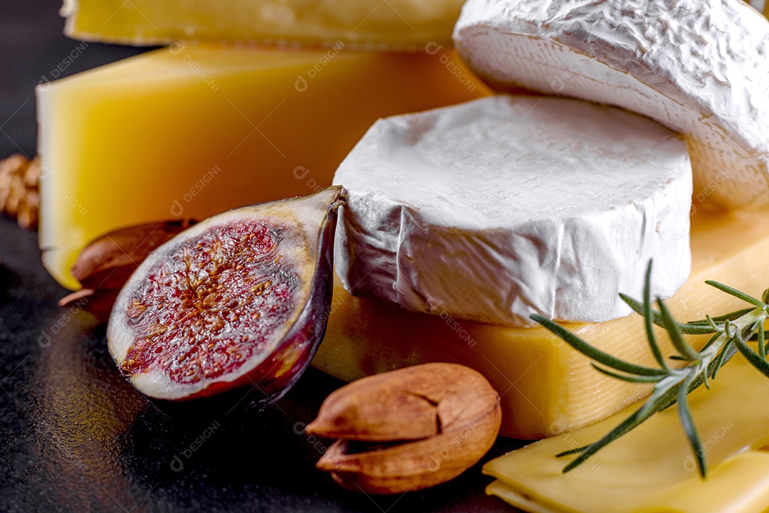 Lindo delicioso queijo camembert, parmesão, brie com uvas e figos em uma tábua de madeira.