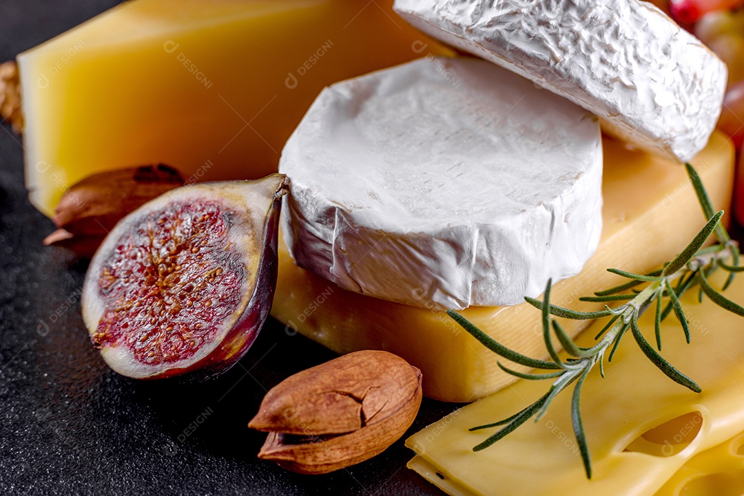 Lindo delicioso queijo camembert, parmesão, brie com uvas e figos em uma tábua de madeira.