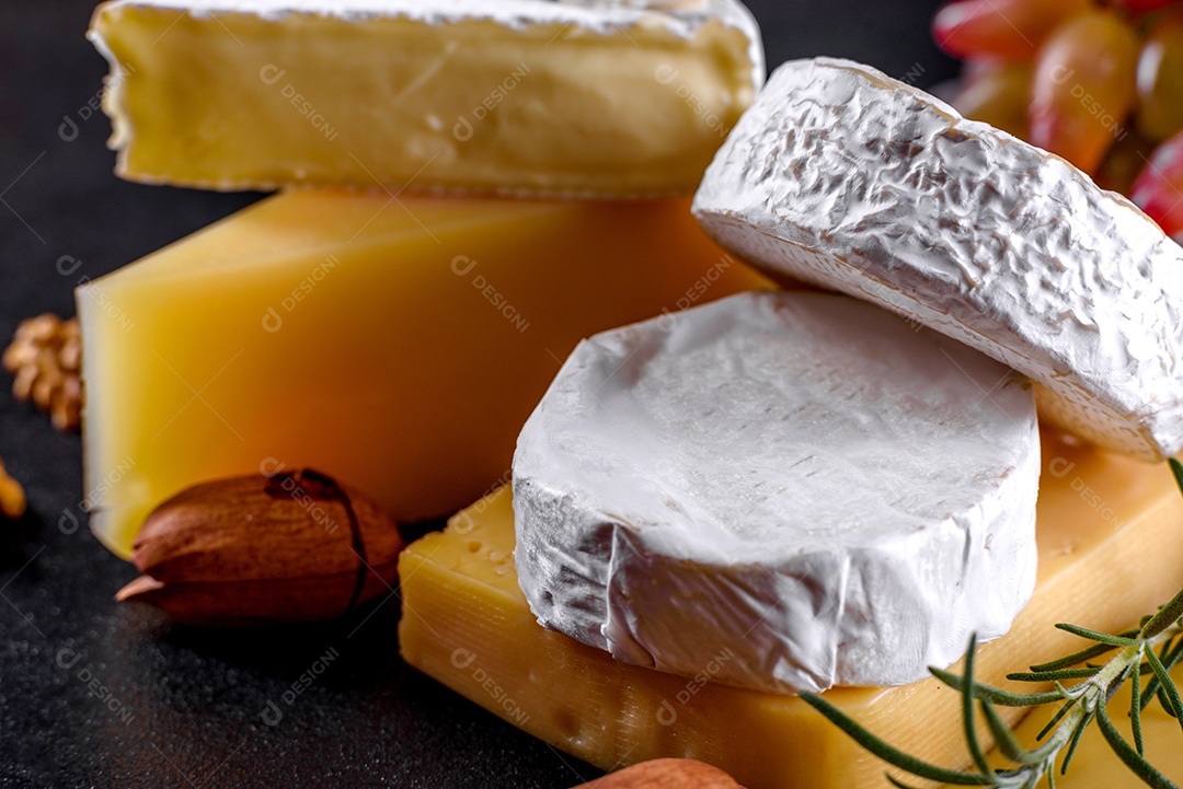 Lindo delicioso queijo camembert, parmesão, brie com uvas e figos em uma tábua de madeira.