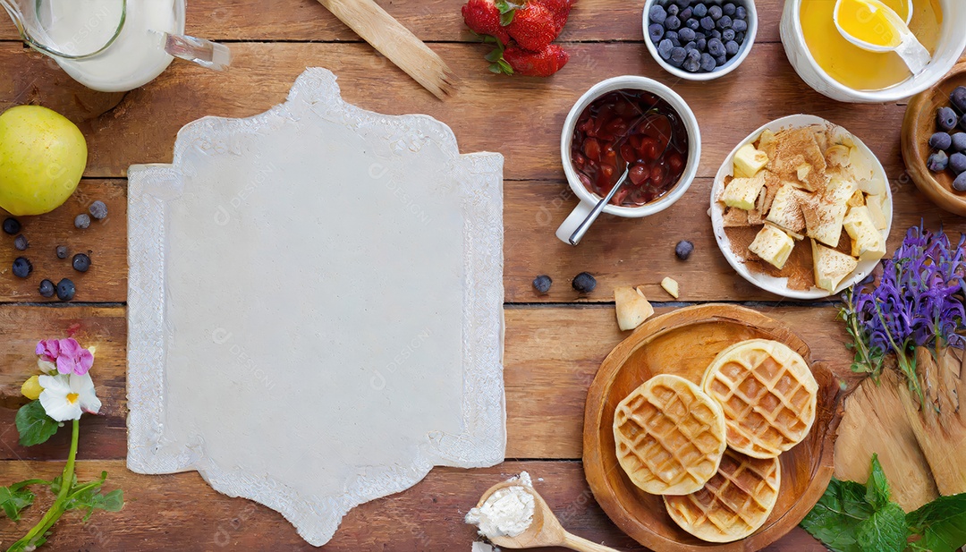 Waffles belgas com morangos, mirtilos e calda na mesa de madeira.