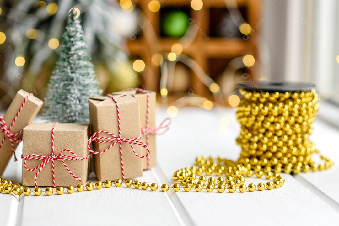 Lindas decorações de Natal multicoloridas sobre uma mesa de madeira clara com guirlandas e árvores de Natal ao fundo.