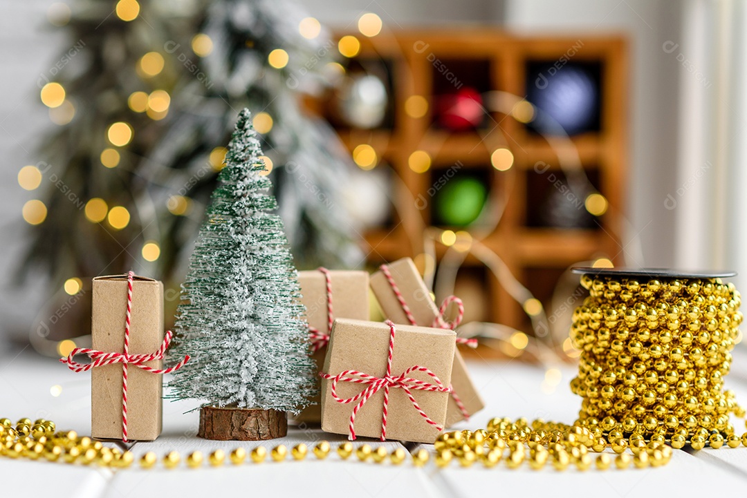 Lindas decorações de Natal multicoloridas sobre uma mesa de madeira clara com guirlandas e árvores de Natal ao fundo.