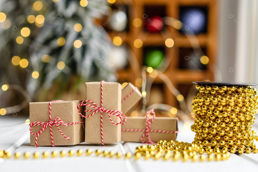 Lindas decorações de Natal multicoloridas sobre uma mesa de madeira clara com guirlandas e árvores de Natal ao fundo.