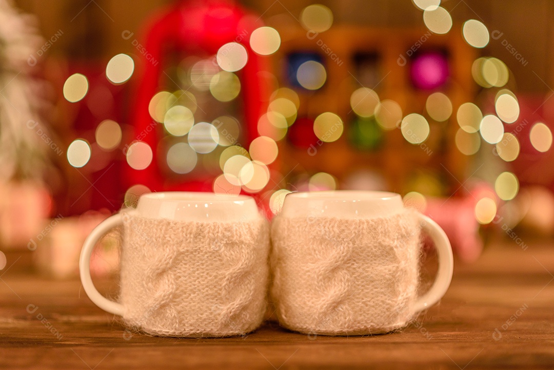 Lindas decorações de Natal multicoloridas em uma mesa de madeira com guirlandas e árvores de Natal ao fundo.