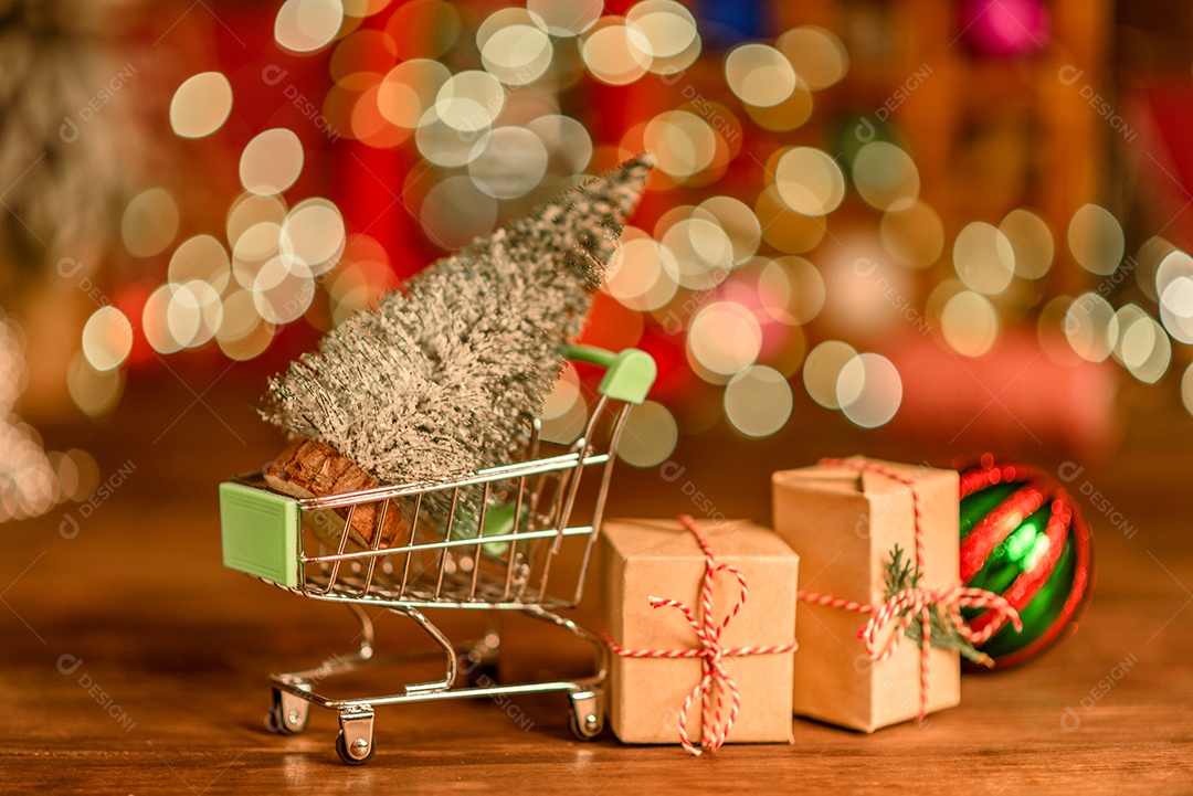 Lindas decorações de Natal multicoloridas em uma mesa de madeira com guirlandas e árvores de Natal ao fundo.
