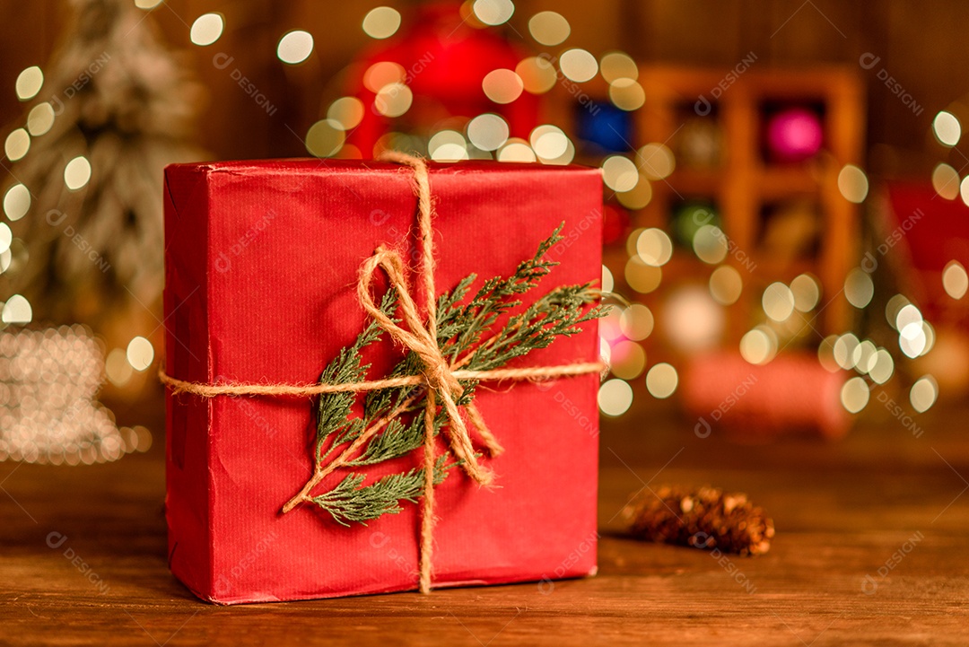 Lindas decorações de Natal multicoloridas em uma mesa de madeira com guirlandas e árvores de Natal ao fundo.