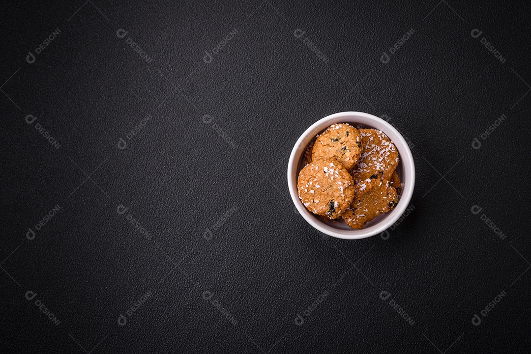 Deliciosos biscoitos redondos e doces polvilhados com flocos de coco sobre um fundo escuro de concreto