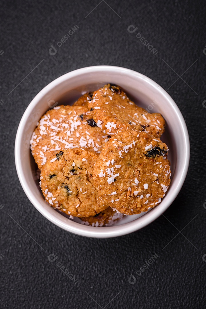 Deliciosos biscoitos redondos e doces polvilhados com flocos de coco sobre um fundo escuro de concreto