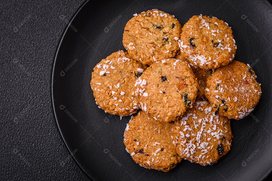 Deliciosos biscoitos redondos e doces polvilhados com flocos de coco sobre um fundo escuro de concreto