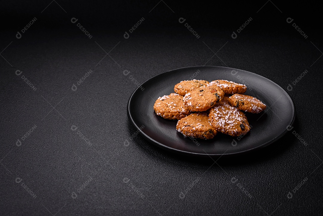 Deliciosos biscoitos redondos e doces polvilhados com flocos de coco sobre um fundo escuro de concreto
