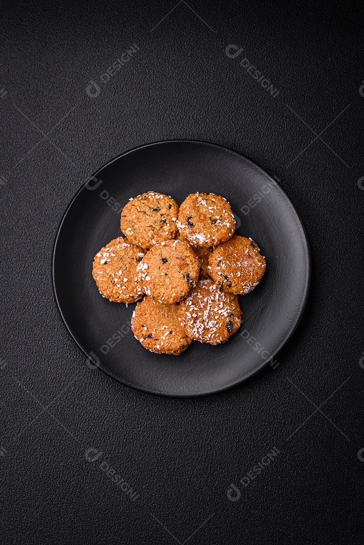 Deliciosos biscoitos redondos e doces polvilhados com flocos de coco sobre um fundo escuro de concreto
