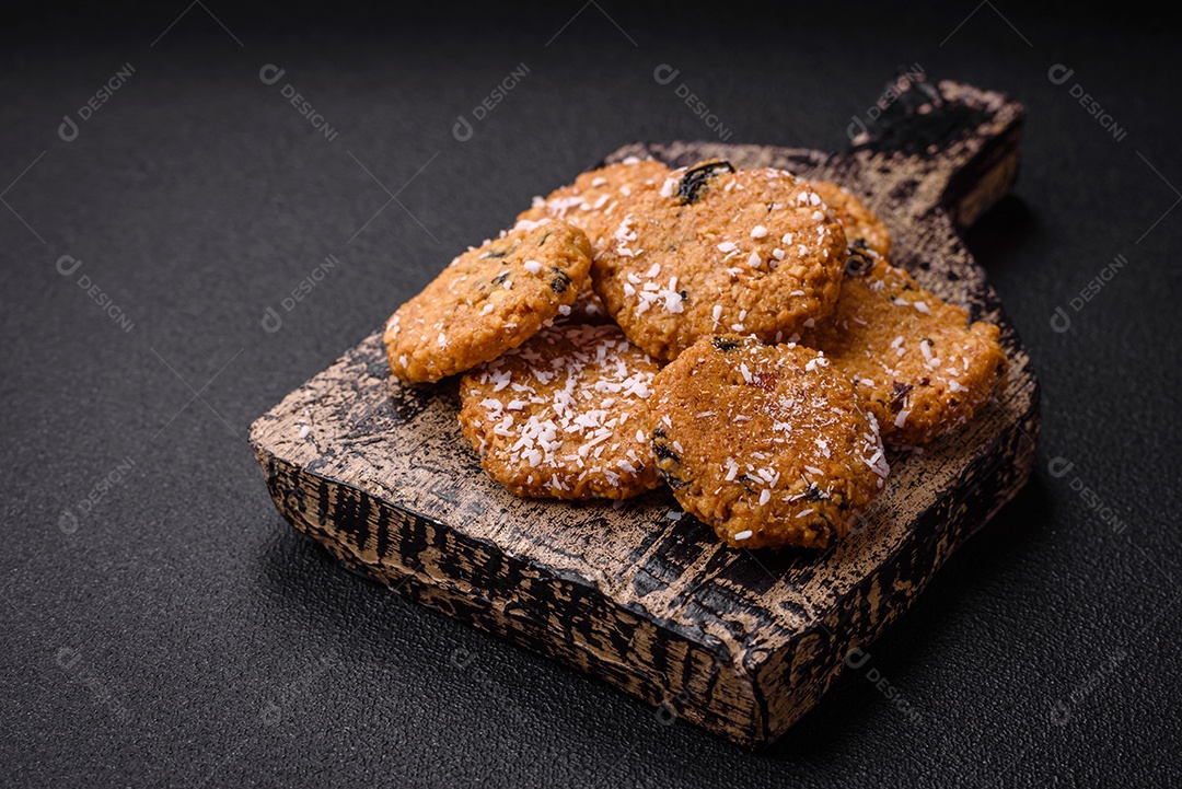 Deliciosos biscoitos redondos e doces polvilhados com flocos de coco sobre um fundo escuro de concreto