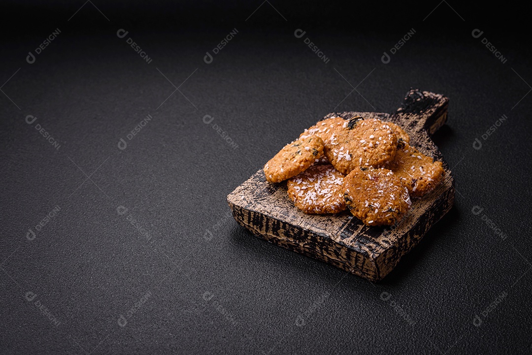 Deliciosos biscoitos redondos e doces polvilhados com flocos de coco sobre um fundo escuro de concreto