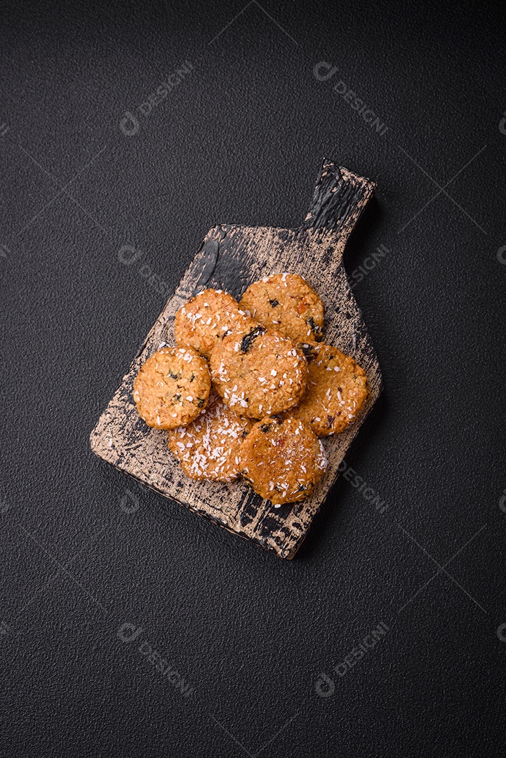 Deliciosos biscoitos redondos e doces polvilhados com flocos de coco sobre um fundo escuro de concreto