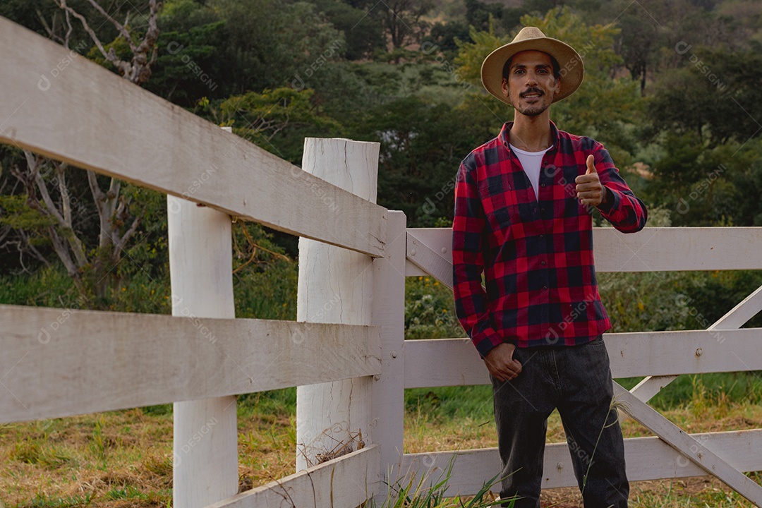 Jovem agricultor negro do sexo masculino trabalhando em frente ao portão dos agricultores.