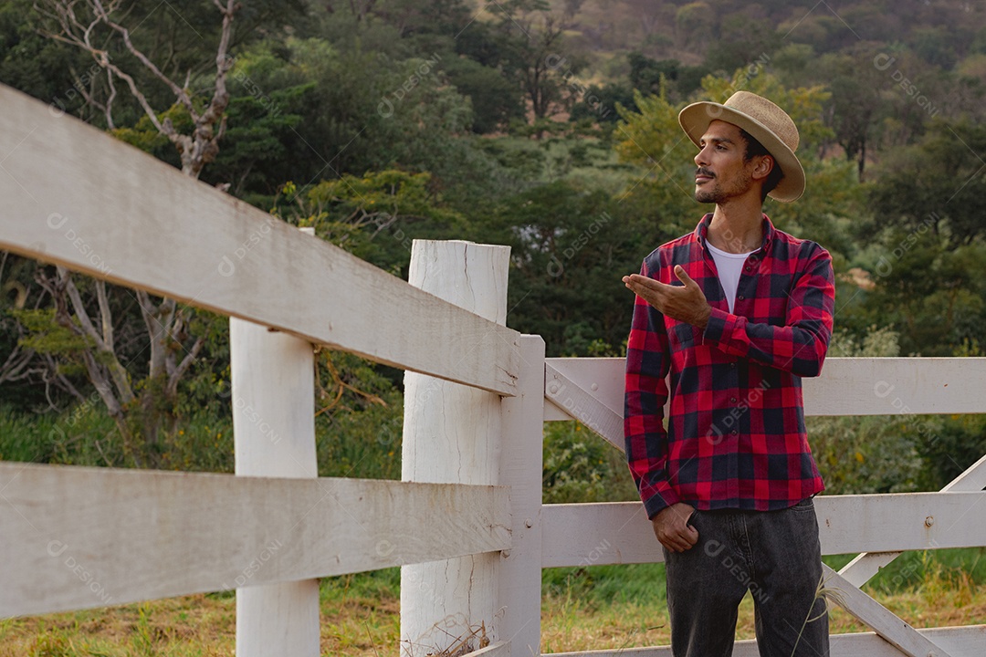 Jovem agricultor negro do sexo masculino trabalhando em frente ao portão dos agricultores.