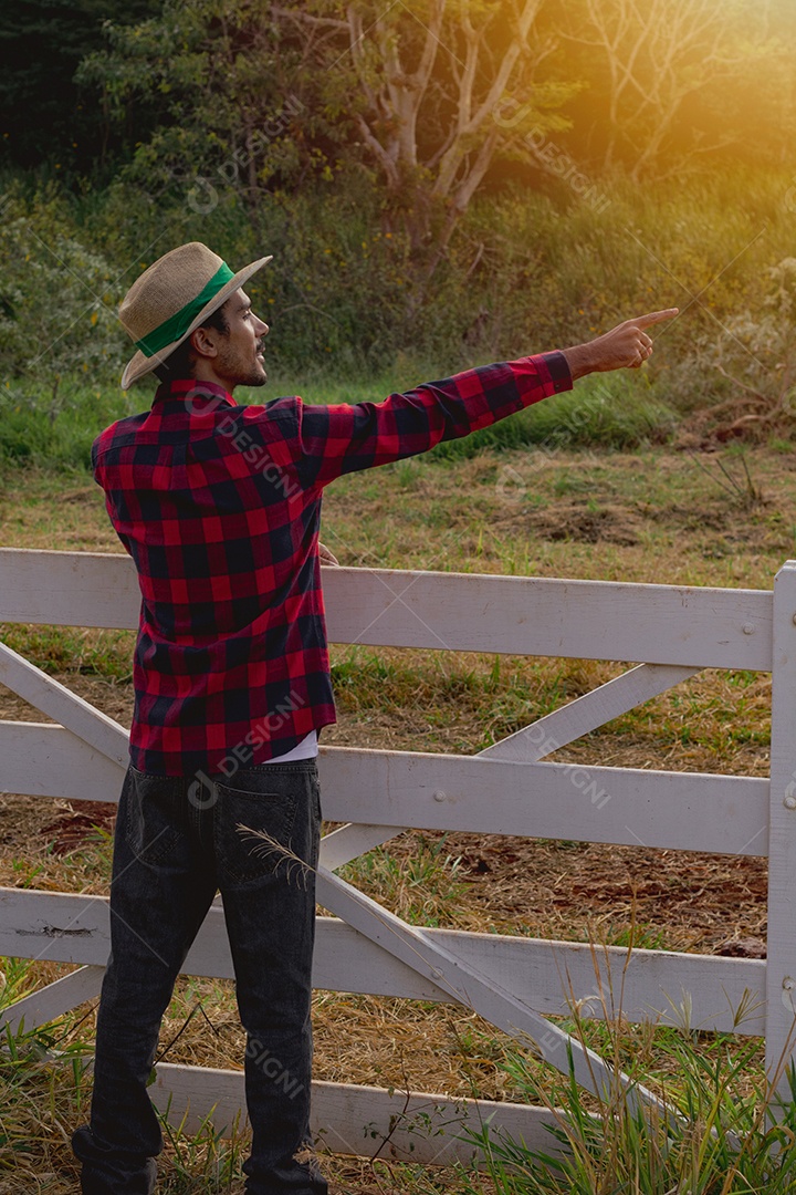 Jovem agricultor negro do sexo masculino trabalhando em frente ao portão dos agricultores.