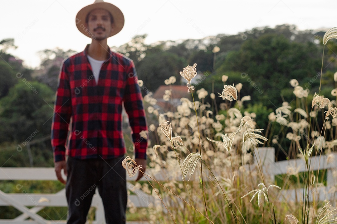 Jovem agricultor negro do sexo masculino trabalhando em frente ao portão dos agricultores.
