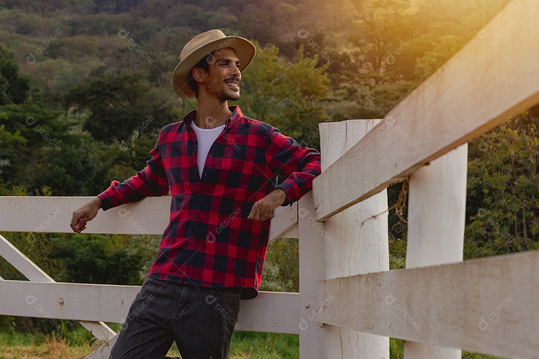 Jovem agricultor negro do sexo masculino trabalhando em frente ao portão dos agricultores.