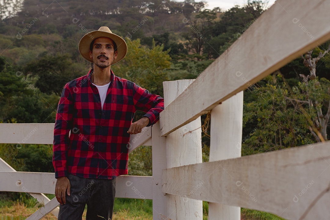 Jovem agricultor negro do sexo masculino trabalhando em frente ao portão dos agricultores.