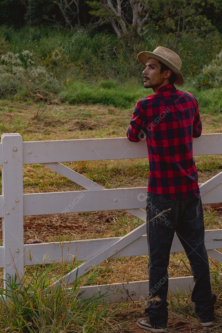 Jovem agricultor negro do sexo masculino trabalhando em frente ao portão dos agricultores.