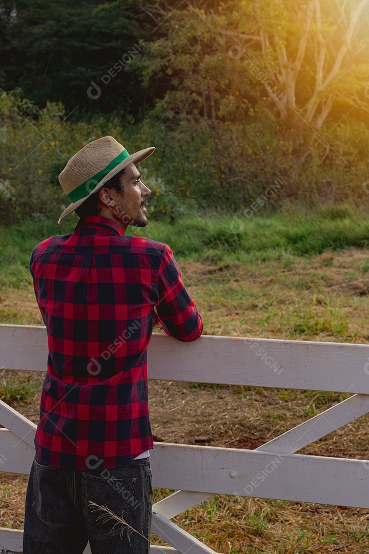 Jovem agricultor negro do sexo masculino trabalhando em frente ao portão dos agricultores.
