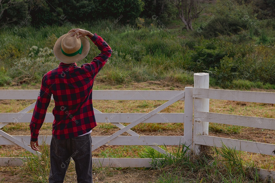 Jovem agricultor negro do sexo masculino trabalhando em frente ao portão dos agricultores.