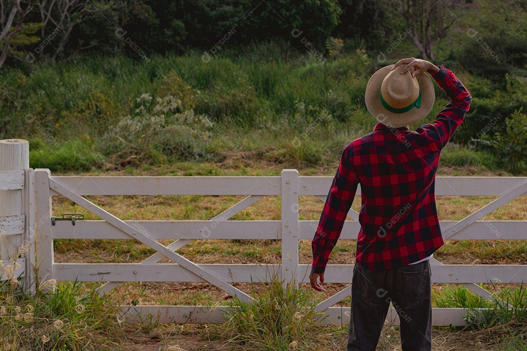 Jovem agricultor negro do sexo masculino trabalhando em frente ao portão dos agricultores.