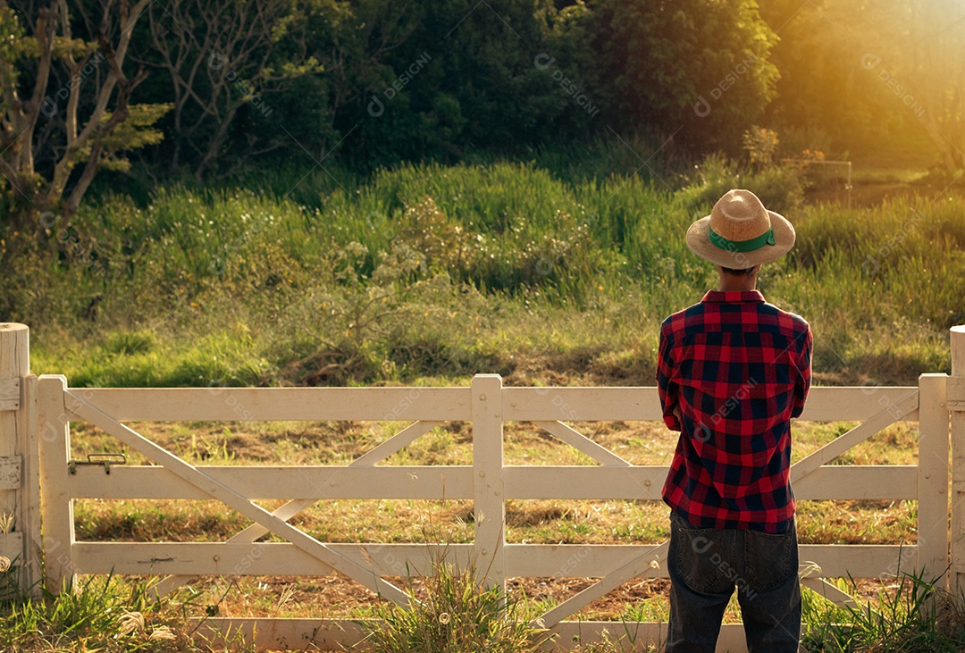 Jovem agricultor negro do sexo masculino trabalhando em frente ao portão dos agricultores.
