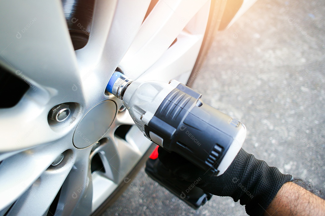 Mecânicos usam chaves de impacto sem fio para remover as porcas das rodas do carro