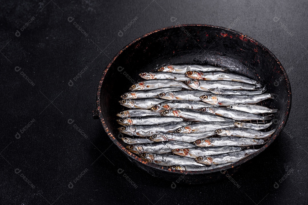 Vários peixes anchovas salgadas em uma mesa de concreto escuro. Conceito de peixes pequenos