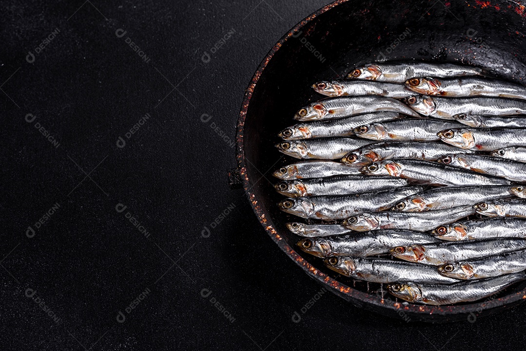 Vários peixes anchovas salgadas em uma mesa de concreto escuro. Conceito de peixes pequenos