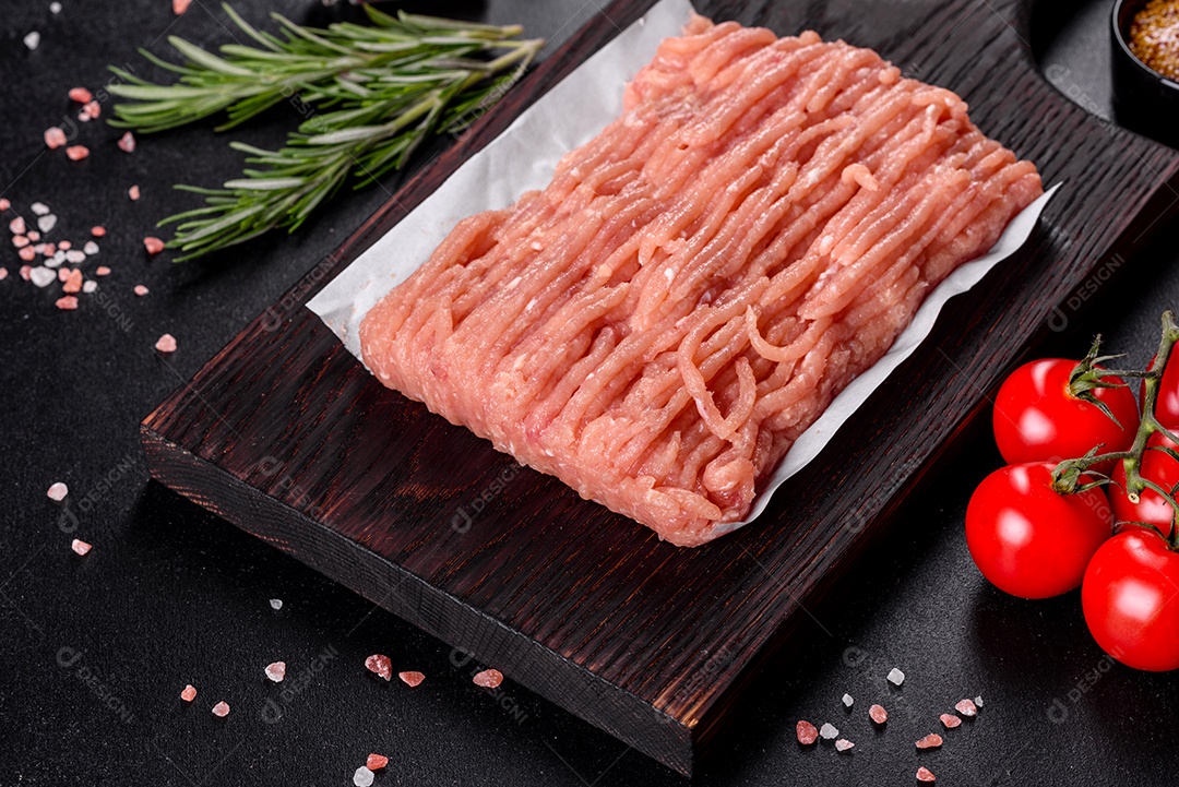 Frango cru fresco picado em uma tábua de madeira escura. Preparação para preparação de costeletas