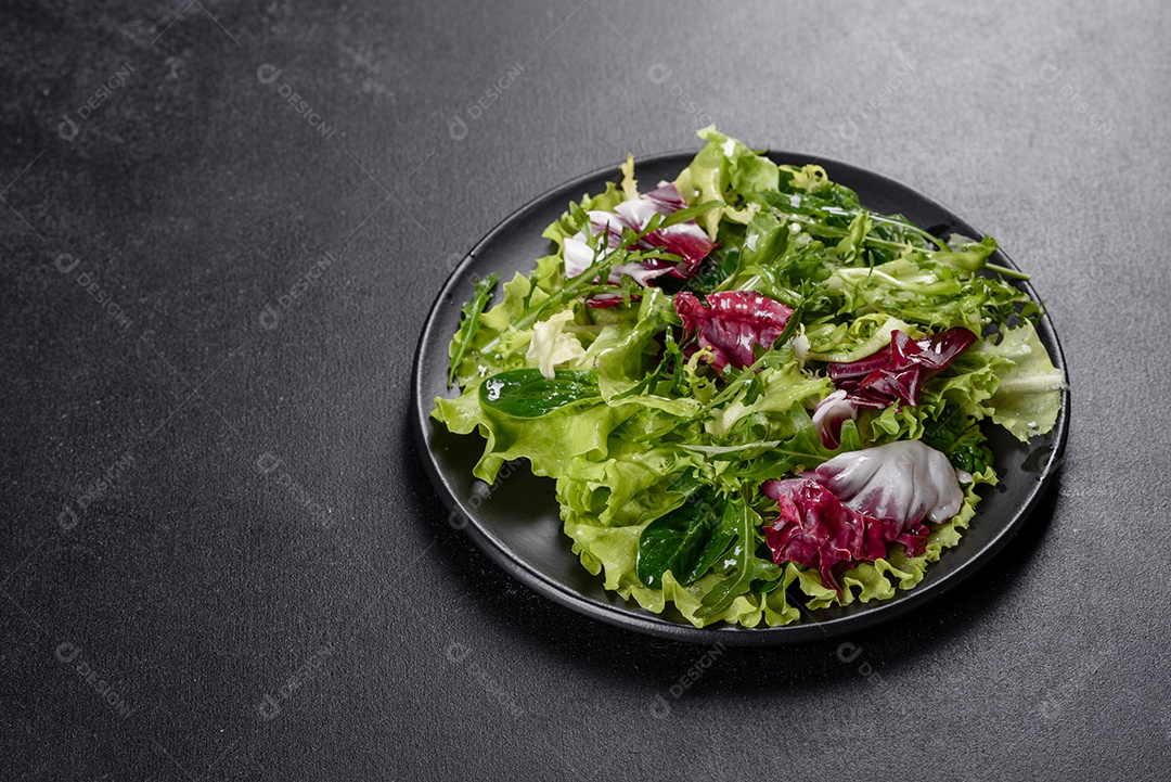 Salada vegetariana deliciosa e fresca de legumes picados em um prato sobre um fundo escuro de concreto