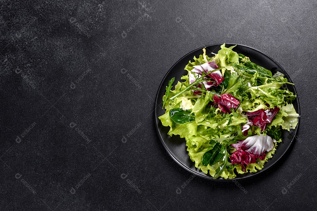 Salada vegetariana deliciosa e fresca de legumes picados em um prato sobre um fundo escuro de concreto