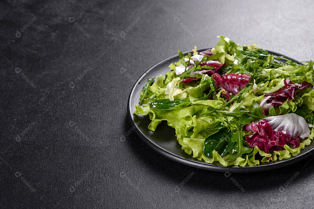 Salada vegetariana deliciosa e fresca de legumes picados em um prato sobre um fundo escuro de concreto