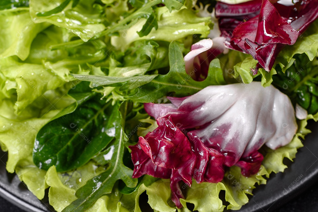 Salada vegetariana deliciosa e fresca de legumes picados em um prato sobre um fundo escuro de concreto