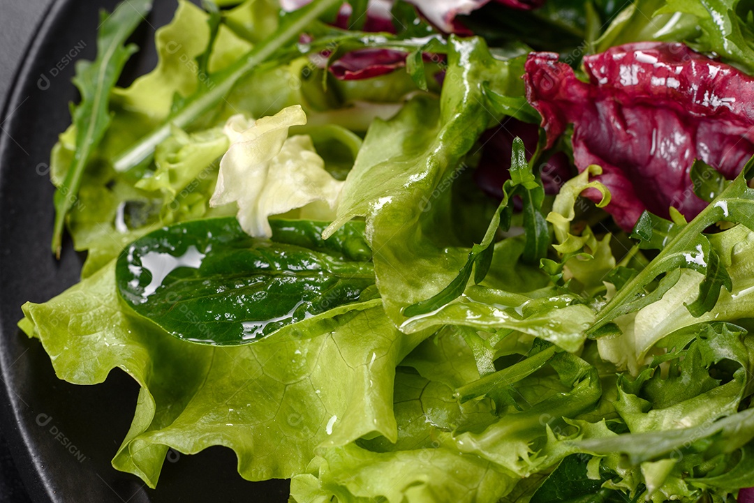 Salada vegetariana deliciosa e fresca de legumes picados em um prato sobre um fundo escuro de concreto