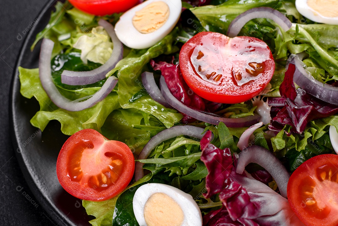 Salada vegetariana deliciosa e fresca de legumes picados em um prato sobre um fundo escuro de concreto