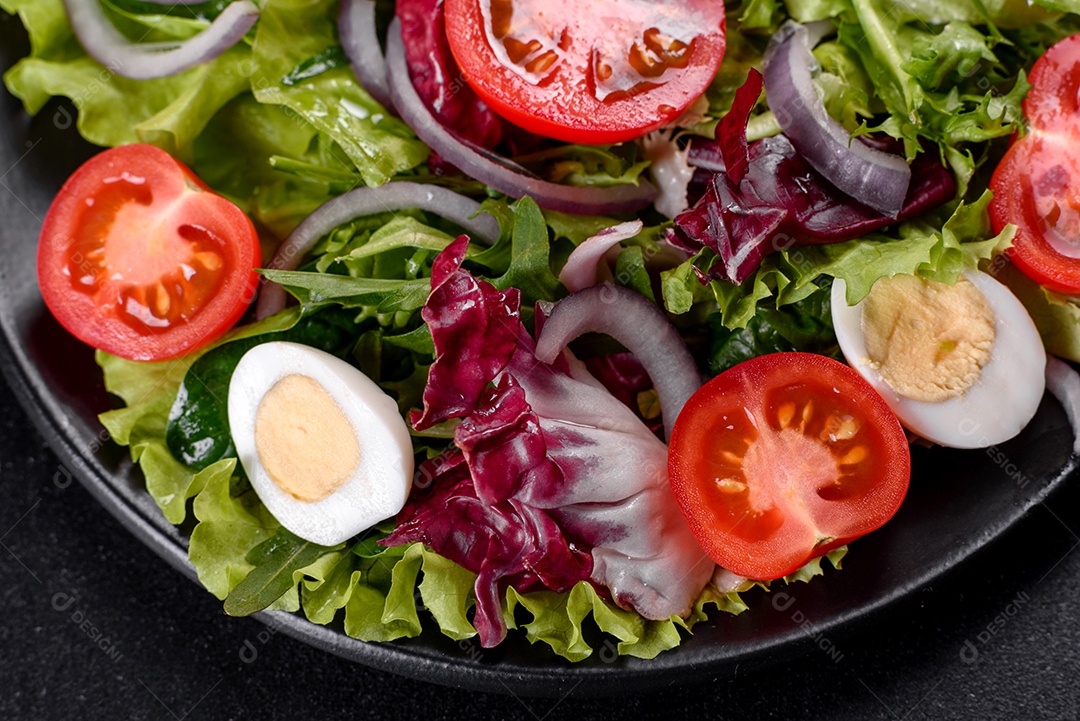 Salada vegetariana deliciosa e fresca de legumes picados em um prato sobre um fundo escuro de concreto