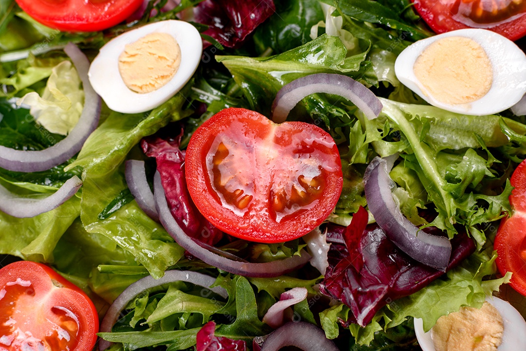 Salada vegetariana deliciosa e fresca de legumes picados em um prato sobre um fundo escuro de concreto