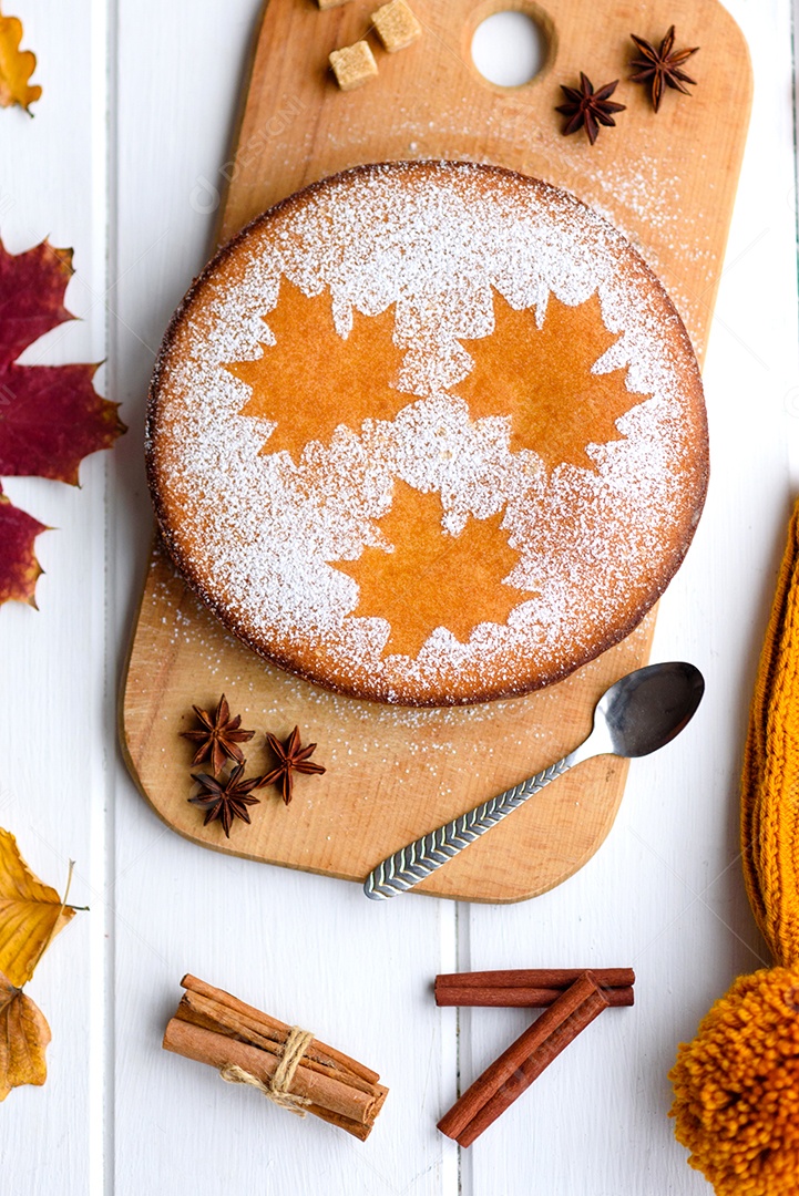 Lindo bolo de abóbora doce fresco com um padrão de folha de bordo sobre um fundo branco de madeira com uma composição de folhas secas de outono