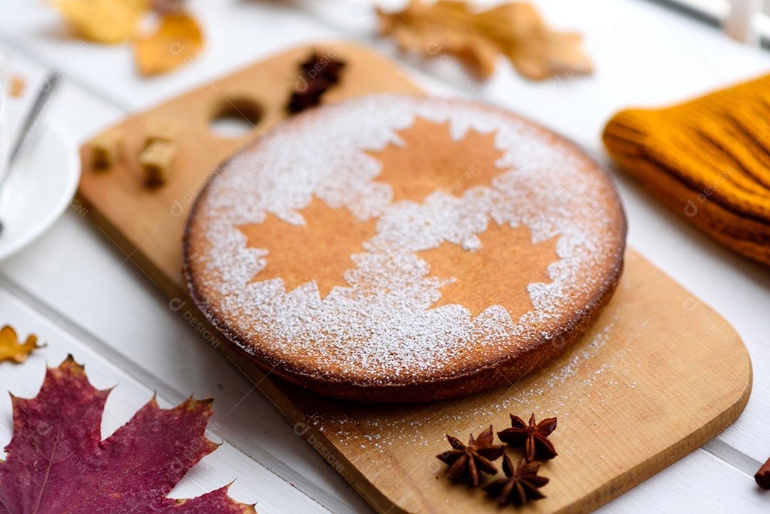 Lindo bolo de abóbora doce fresco com um padrão de folha de bordo sobre um fundo branco de madeira com uma composição de folhas secas de outono