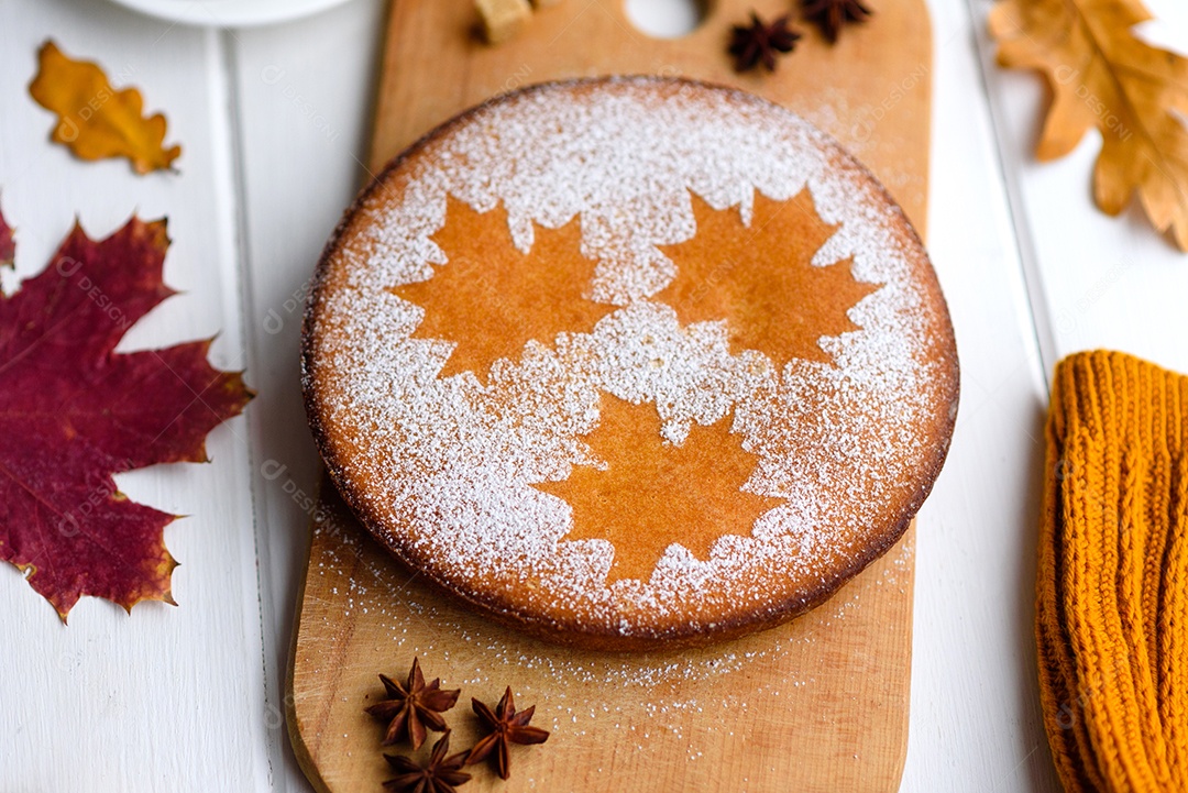 Lindo bolo de abóbora doce fresco com um padrão de folha de bordo sobre um fundo branco de madeira com uma composição de folhas secas de outono