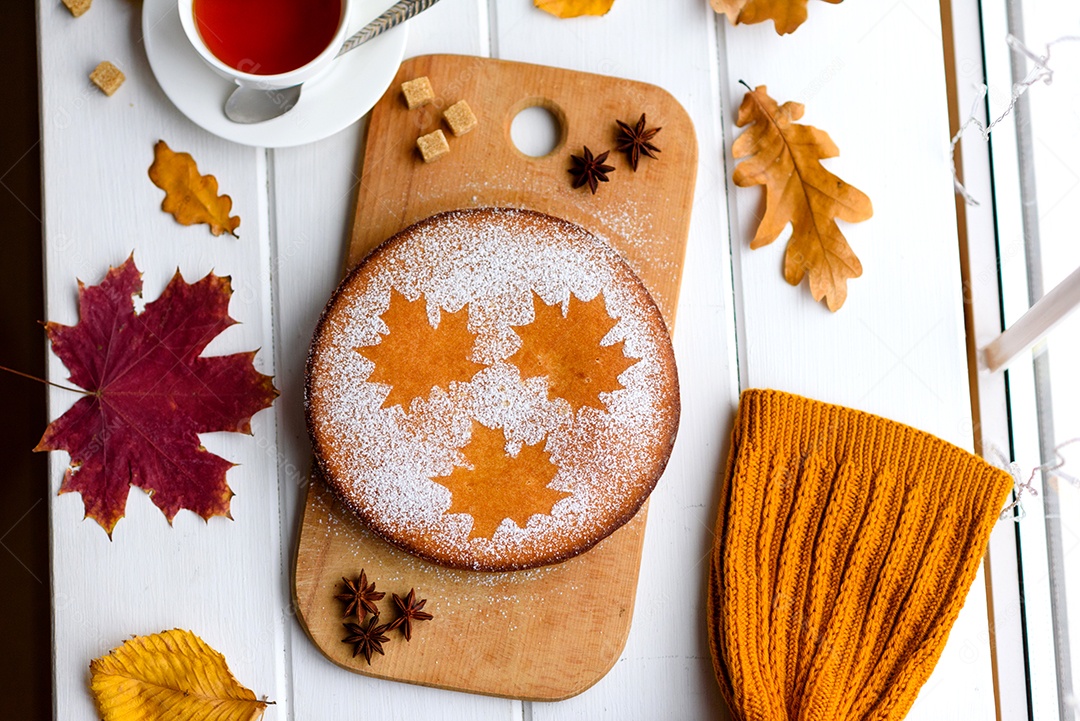 Lindo bolo de abóbora doce fresco com um padrão de folha de bordo sobre um fundo branco de madeira com uma composição de folhas secas de outono