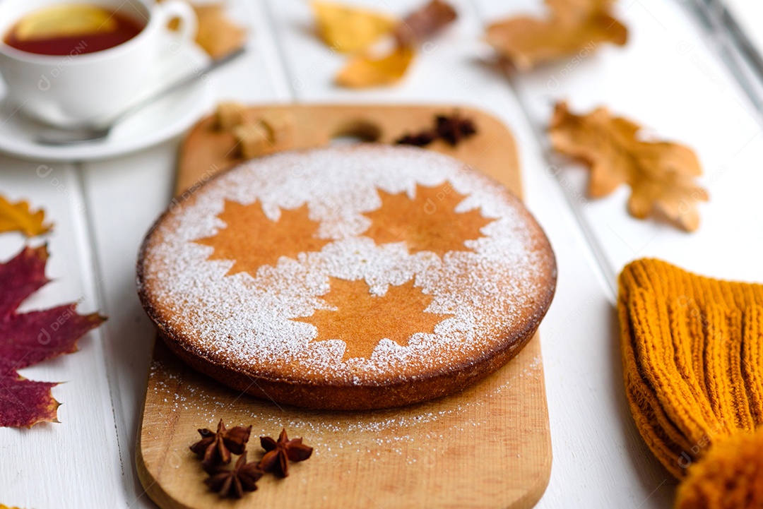 Lindo bolo de abóbora doce fresco com um padrão de folha de bordo sobre um fundo branco de madeira com uma composição de folhas secas de outono